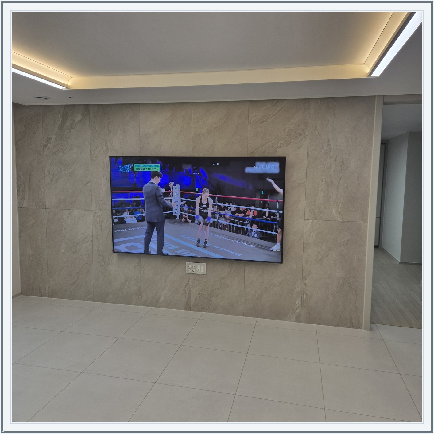 돌무늬 패널과 대형 TV, TV 아래 콘센트 패널이 드러나는 구도입니다