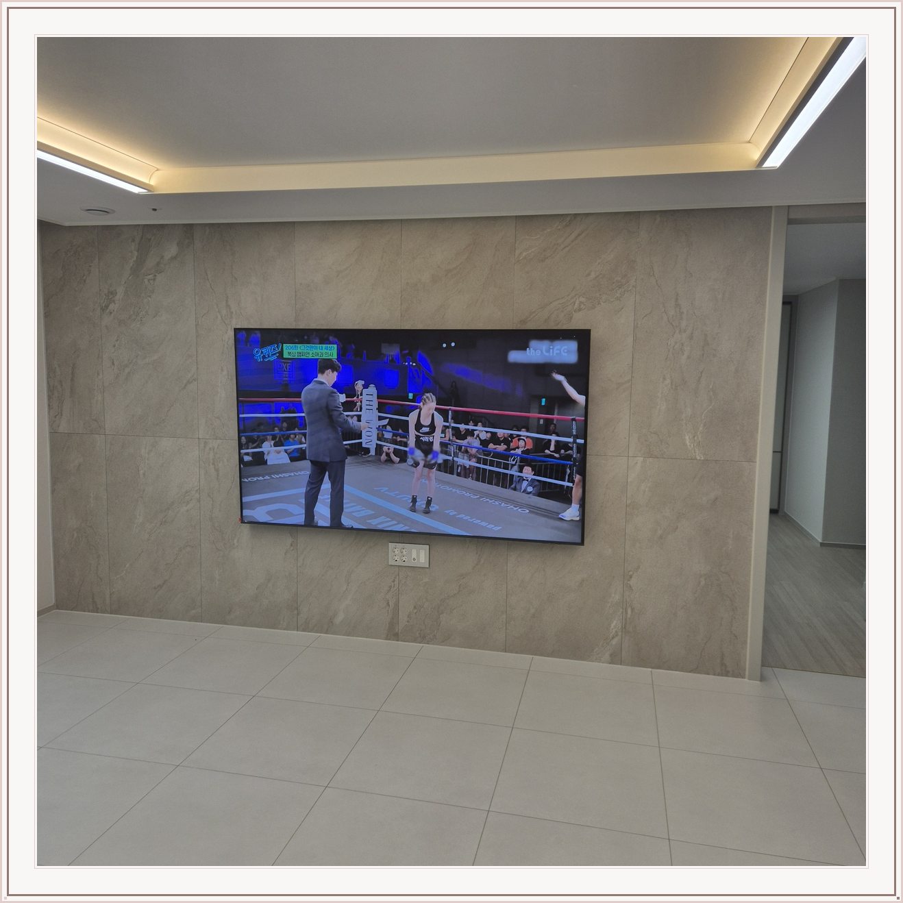 돌무늬 패널과 대형 TV, TV 아래 콘센트 패널이 드러나는 구도입니다