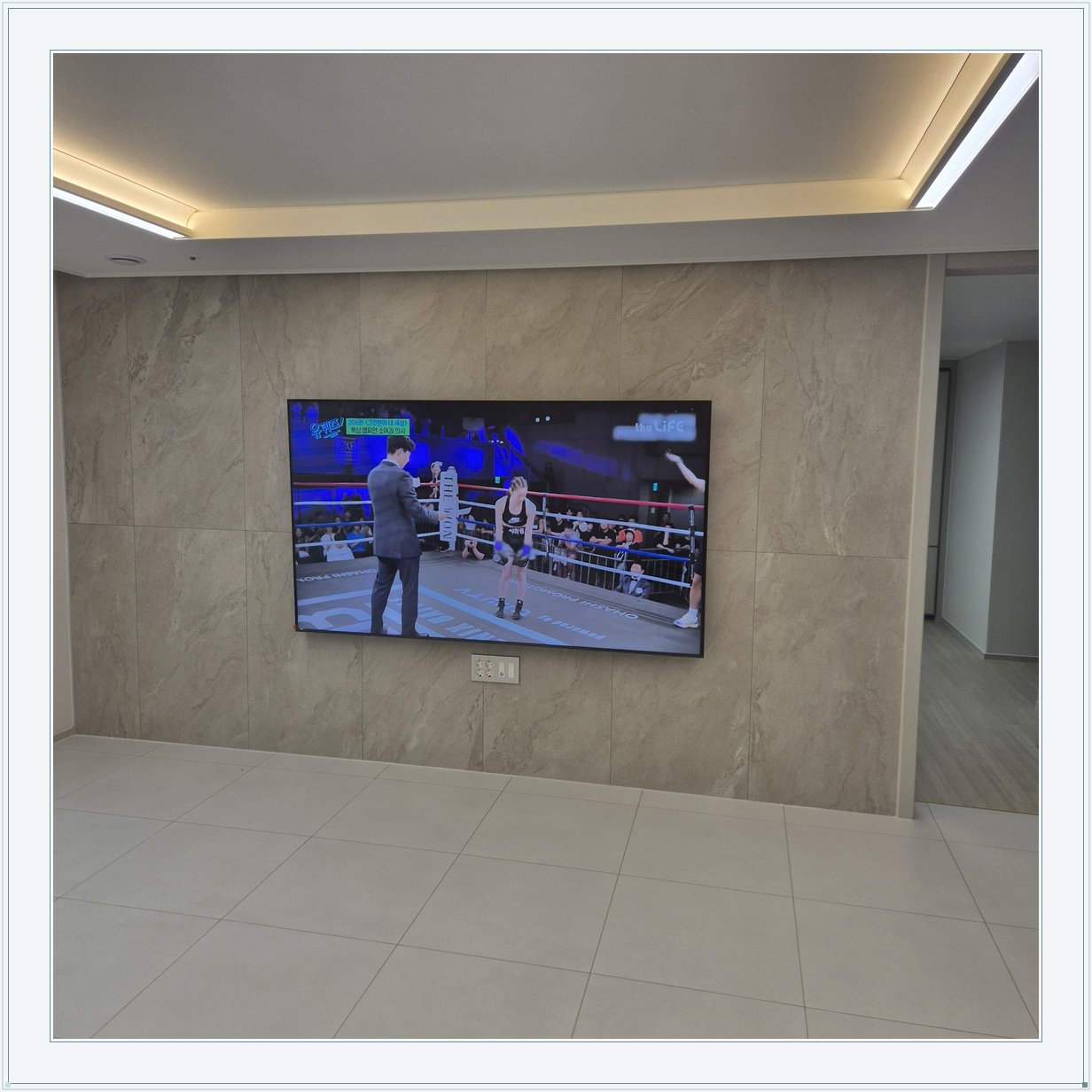 돌무늬 패널과 대형 TV, TV 아래 콘센트 패널이 드러나는 구도입니다