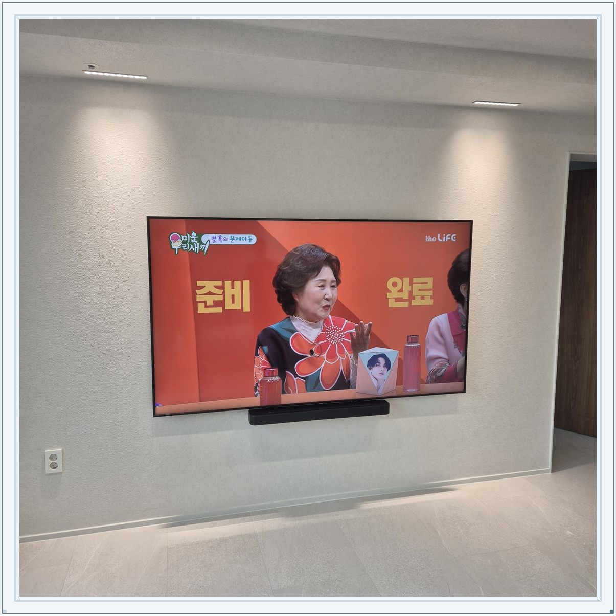 조명이 비추는 미색 벽과 사운드바, 사운드바와 벽면의 간격이 한눈에 들어옵니다